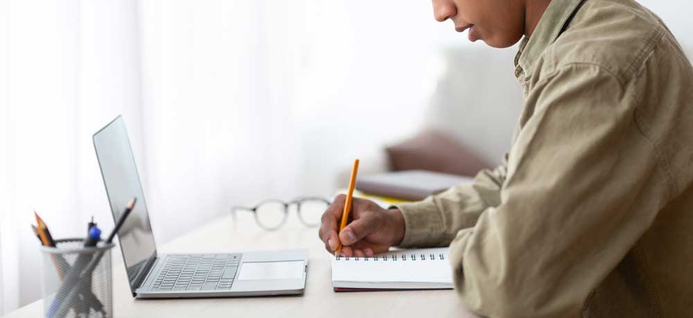 Person sitting at desk with computer and notebook 