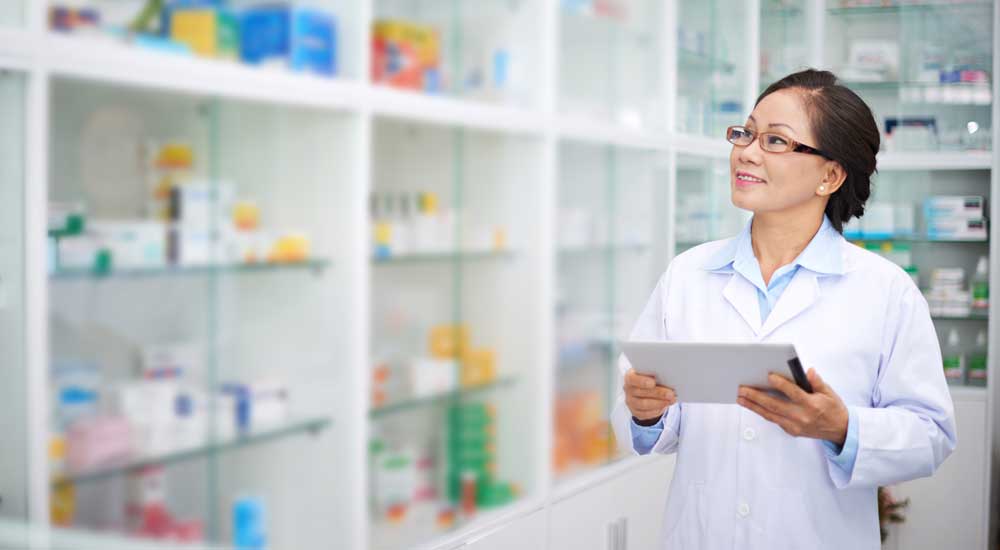 woman in white coat with clipboard and row of pill bottles
