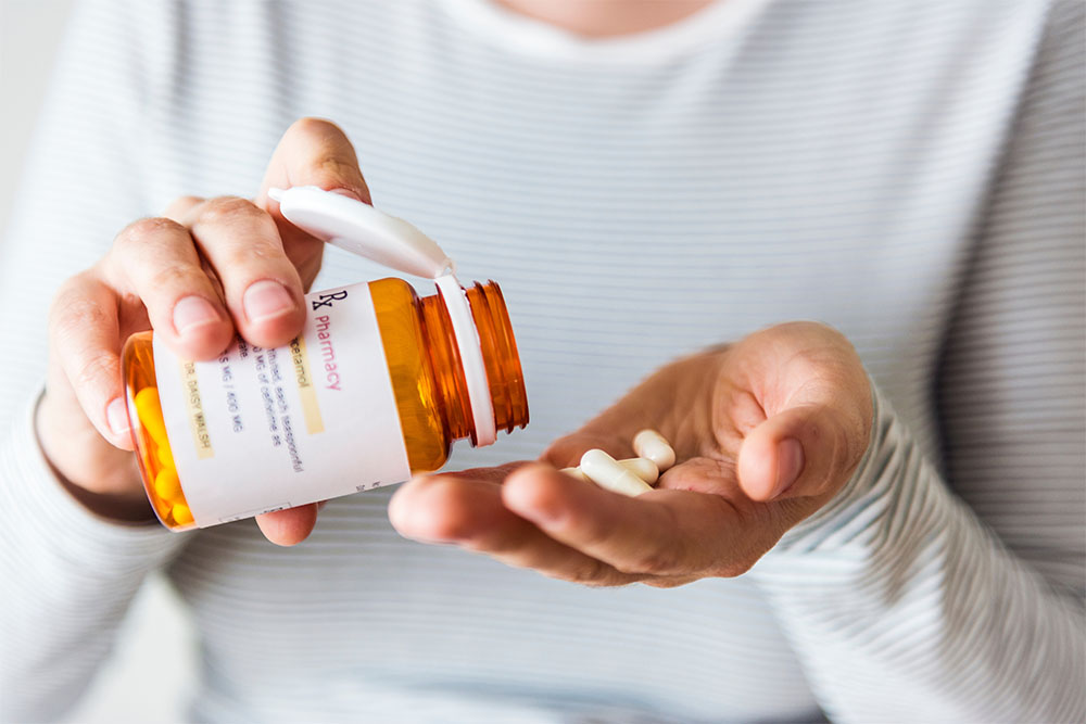 close up of hands holding prescription bottle and pills