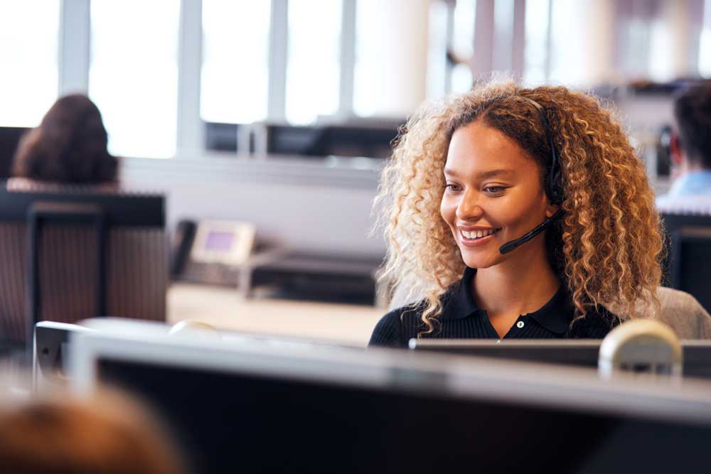 Woman with headset in front of computer 